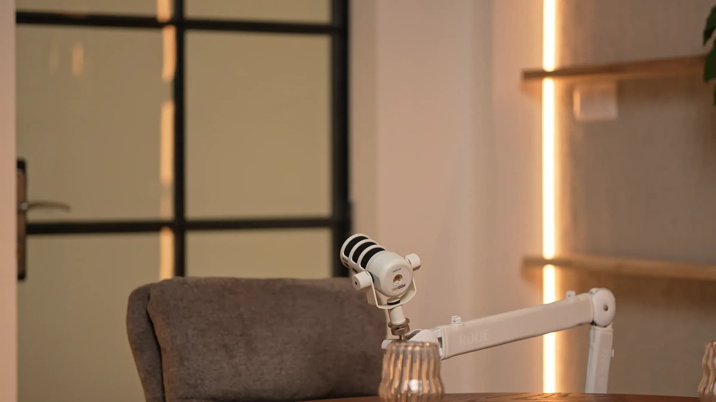 Espresso Room: fehér mikrofon karon, szürke fotel, üvegajtó fekete kerettel