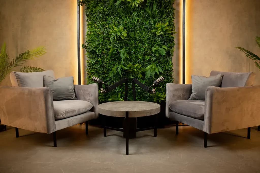 Botanic Loft: két szürke fotel meleg fényben, kerek asztal, zöld növényfal